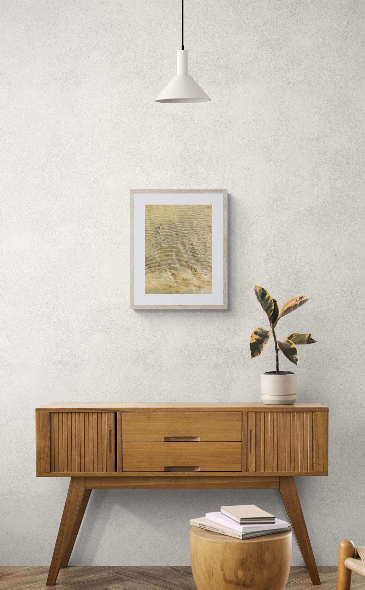 framed photo of wet sand hanging above wooden console table with plant on it.
