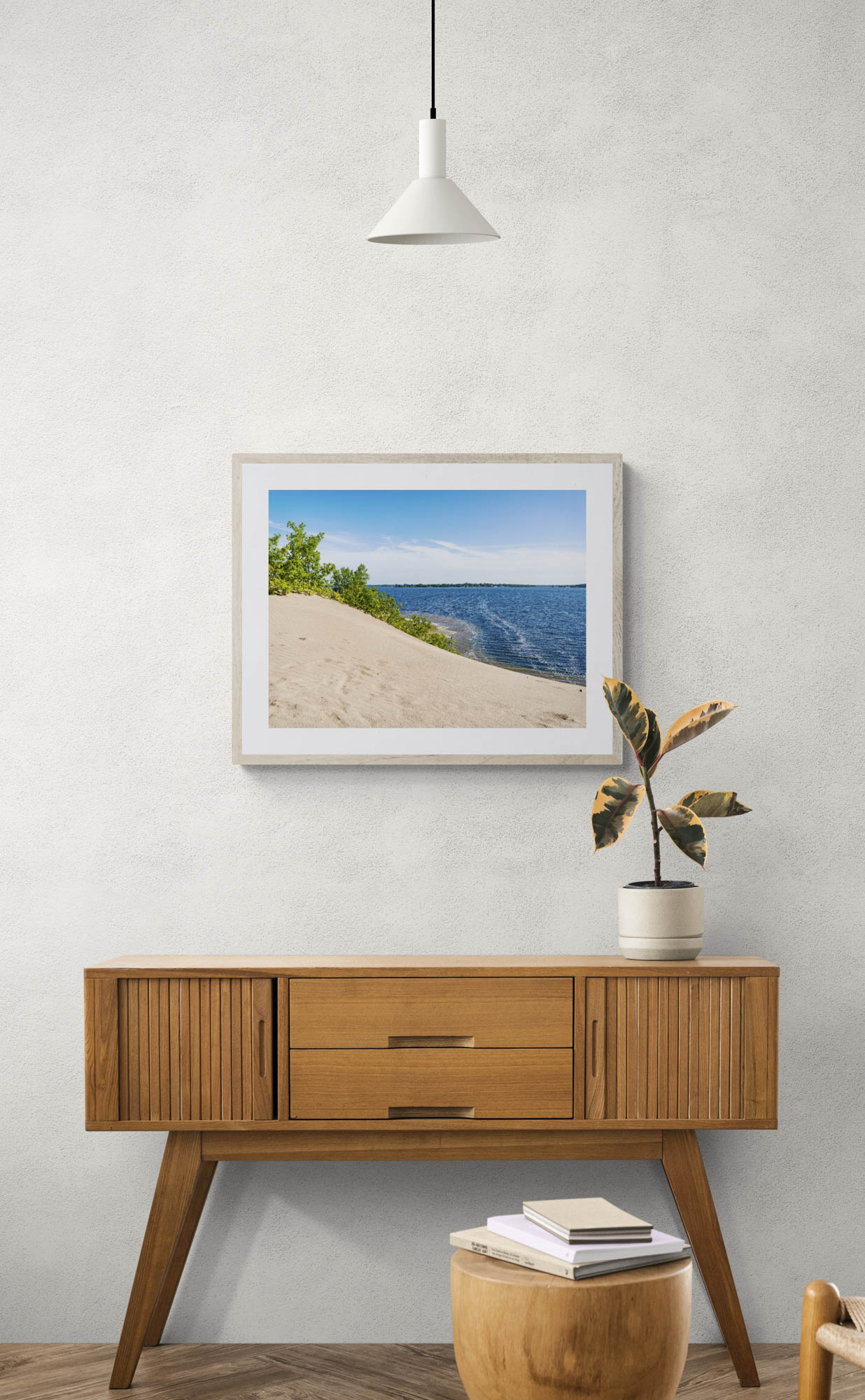 mockup of framed sand dune with water photo hanging above wooden console table.