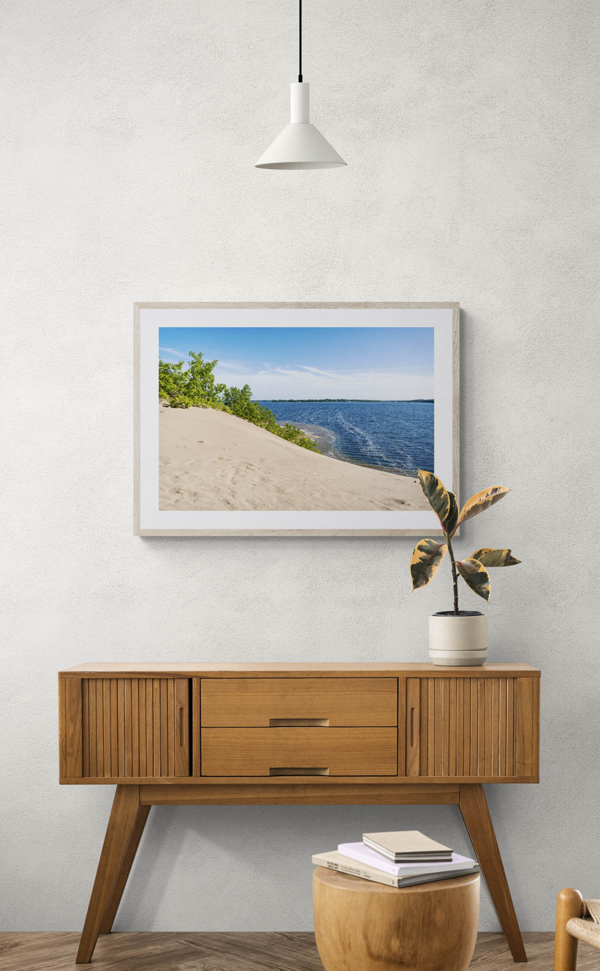 mockup of framed sand dune with water photo hanging above wooden console table.